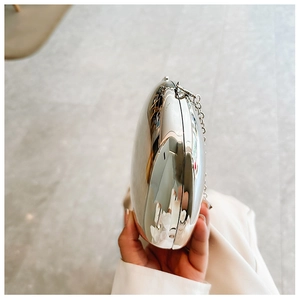Close-up of a silver egg-shaped metallic clutch with a high mirror finish and chain