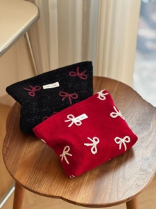 Quilted fabric cosmetic bags with embroidered bow and simple wish tag on a wooden stool