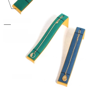 Macro view of curved velvet jewelry display stand with gold metal base and necklaces