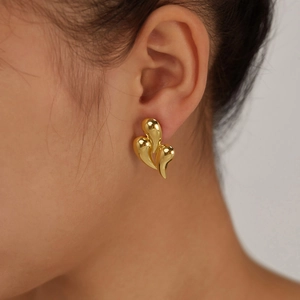Close-up of gold plated triple layer teardrop earrings worn by a model in natural light
