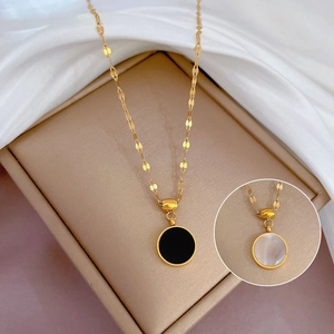 Detail of gold titanium necklace featuring reversible black and white mother of pearl pendant