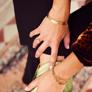 Detailed close-up of 18k gold-plated jewelry set with wave ring and layered bracelets