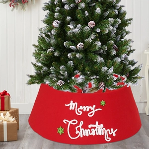 Red fabric Christmas tree skirt with Merry Christmas text and green snowflake patterns