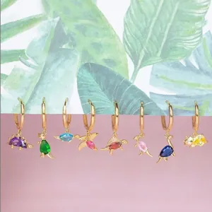 Close-up of dinosaur earrings set featuring colorful cubic zirconia on gold bases