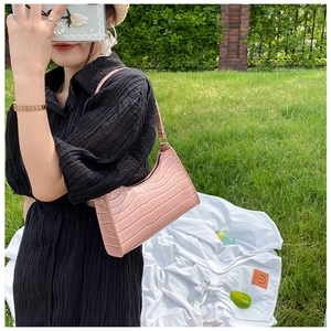 Close-up of pink faux leather underarm bag with crocodile pattern texture