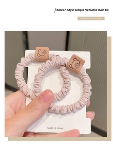 Detail of pink scrunchies with cute bear tags on white card held by hand