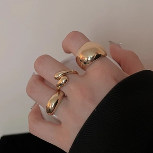 Detailed view of three minimalist irregular gold polished rings worn on fingers