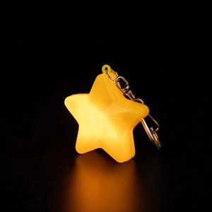 Luminous yellow five-pointed star keychain with metal chain on a black background