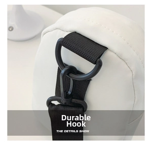 Close-up of durable black D-ring buckle and nylon strap detail on a white crossbody bag