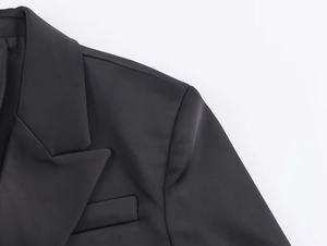 Dettaglio ravvicinato del rever in raso e della cucitura della spalla su blazer nero