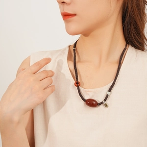 Detail of red agate necklace with silver pendant on waxed cord shown on model