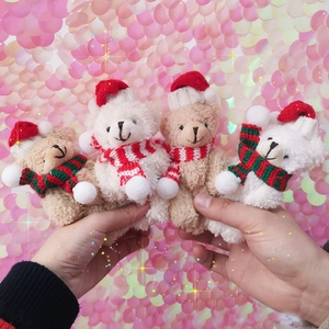Close-up of four plush teddy bears wearing mini red knit hats and striped scarves