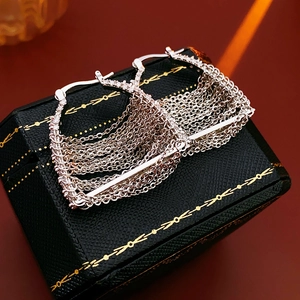 Detail of silver multi-layered chain tassel earrings on a textured jewelry box