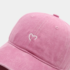Nahaufnahme der rosa gewaschenen Baumwollkappe mit hochwertiger weißer Herzstickerei