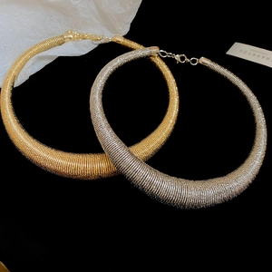 Detailed macro of gold and silver torque necklaces with fine spiral texture and lobster clasp