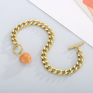 Detail of gold OT buckle chain bracelet with heart-shaped orange stone pendant