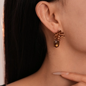 Close-up of retro matte flower earrings with a dark brown oval gemstone drop on model