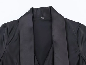 Detail of elegant black dress showing contrast between satin lapel and matte fabric texture