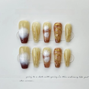 Detail of handmade coffin nails with amber swirls and 3D gold accents on a display card