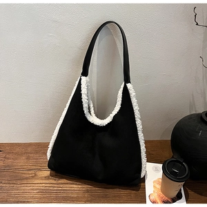 Detail of minimalist black tote bag with white faux fur trim on a wooden table