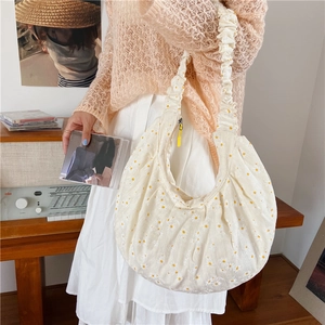 Detail of white daisy print canvas bag featuring a unique ruffled shoulder strap design