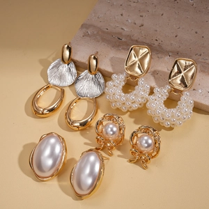 Detailed set of golden faux pearl earrings with floral and textured metal charms