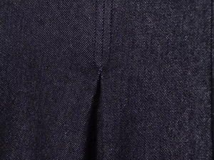 Close-up of deep blue denim fabric texture and detailed stitching on high waist jeans