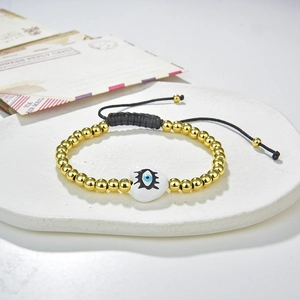 Detail of beaded evil eye bracelet with golden beads and white heart on a stone stand