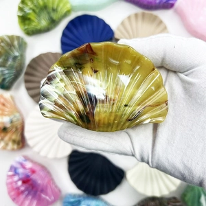 Macro detail of amber marble pattern fan-shaped hair clip held in a gloved hand