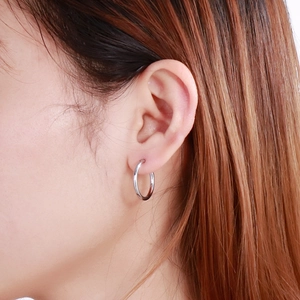 Close-up of a minimalist silver hoop earring worn by a model to show product scale