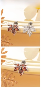 Detailed view of maple leaf stud earrings with red and white marquise-cut zircon stones