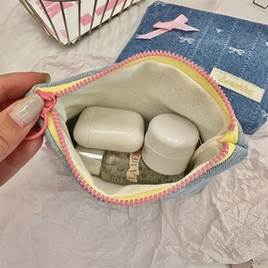 Close-up of denim coin purse with bow embroidery and pink zipper showing storage interior