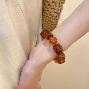 Détail d'un bracelet en perles d'acrylique ambré avec des pierres de résine larges