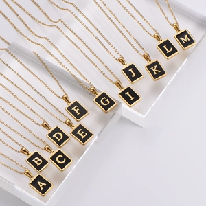 Elegant gold square letter necklaces with black enamel charms for women on display stand