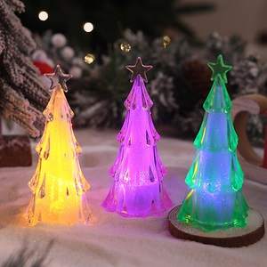 Close-up of mini acrylic LED Christmas trees with colorful glitter in artificial snow