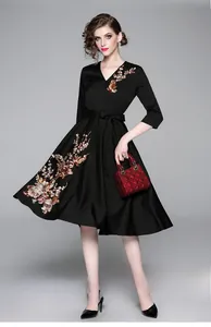 Dettaglio dell'elegante abito in raso nero con scollo a V e raffinato ricamo floreale