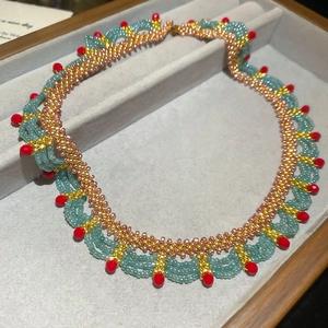 Macro detail of hand-beaded lace choker with blue, gold, and red crystal seed beads