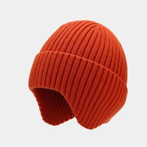 Detail of rib-knit texture on a brick red winter earflap beanie with warm lining