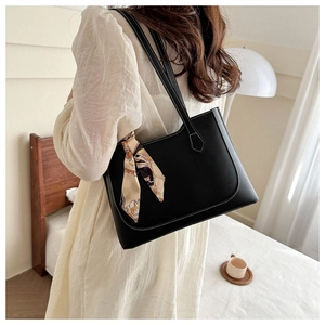 Détail du cabas en cuir noir avec surpiqûres blanches et foulard en soie sur la poignée