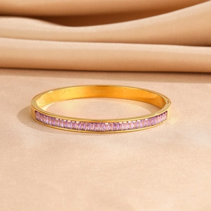 Detail of gold-plated bangle with channel-set purple zircons on champagne silk