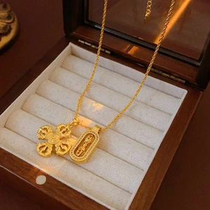Dettaglio ravvicinato di una collana a cilindro dorata con pavé di zirconi e ciondolo vajra