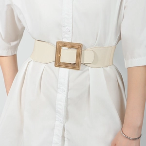 Close-up of beige elastic wide corset belt with gold square woven buckle on white shirt