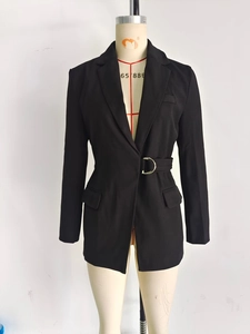 Détail d'un blazer noir cintré avec une boucle dorée et des poches à rabat élégantes