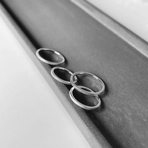 Detail of S925 sterling silver ring with textured ribbed edges on a gray tray