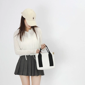 White canvas handbag shown with a beige cap and casual white shirt for a daily look