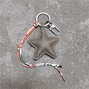 Detail van een stervormige lederen sleutelhanger met stiksels en stoffen band met motief