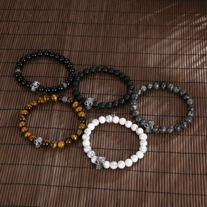 Tiger eye and onyx beaded skull bracelets set displayed on a dark bamboo mat background