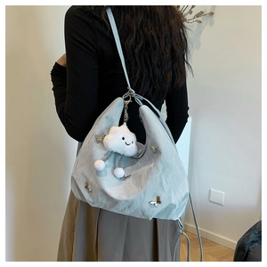 Light blue tote bag with butterfly ornament and plush cloud charm on a female model