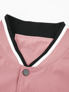 Detail van roze sportjas met zwarte geribbelde kraag en een matte metalen drukknoop