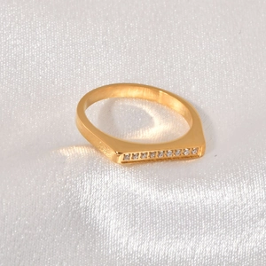 Macro shot of gold D-shape ring with embedded pavé crystals on elegant white silk fabric